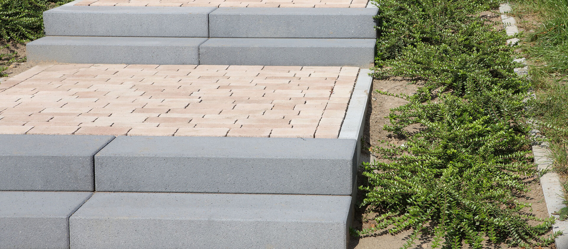 Mehrstufige Freitreppe aus Beton-Blockstufen in Silbergrau vor einem modernen Gebäude