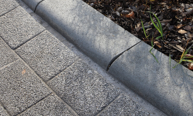 Detailaufnahme eines grauen Rundbordsteins im Landschaftsbau