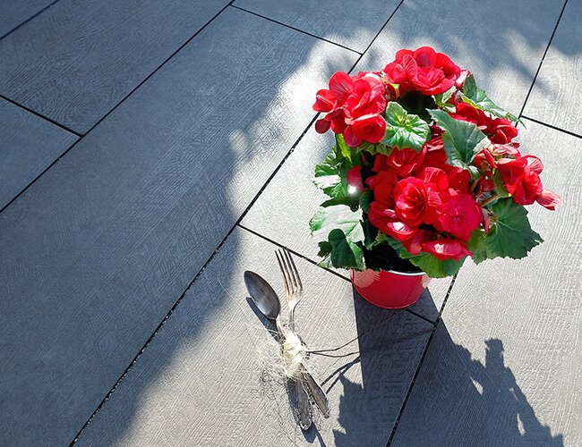 Ambientbild einer Terrasse mit Strukturdiele anthrazit mit Blumen